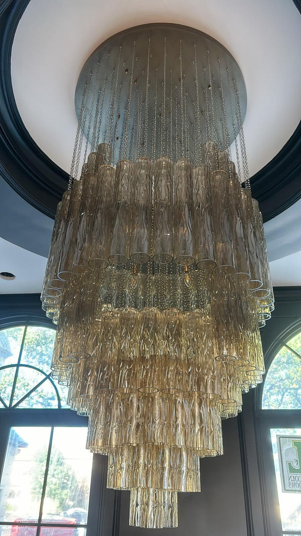 Large chandelier hanging from a ceiling with windows in the background