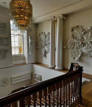 Decorative interior with ornate wall pieces, a chandelier, and a staircase.